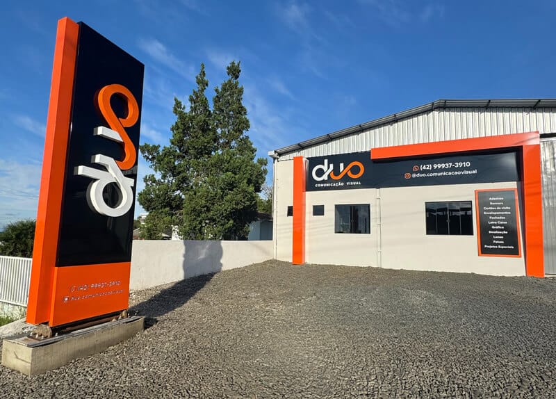 Fachada Duoprinti Imagem da fachada da empresa Duoprinti com um pátio bem limpo um barracão pré-moldado personalizado com uma fachada em ACM e o totem da empresa a frente.